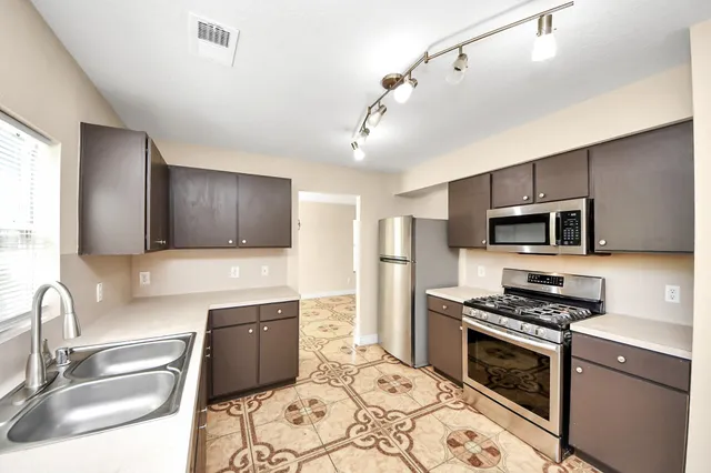 a kitchen with stainless steel appliances a stove sink microwave and cabinets