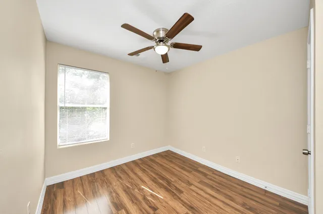 an empty room with wooden floor ceiling fan and a ceiling fan