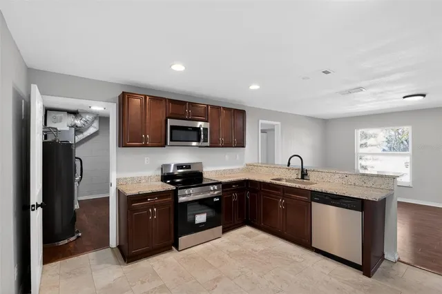 a kitchen with stainless steel appliances granite countertop a sink a stove and a refrigerator