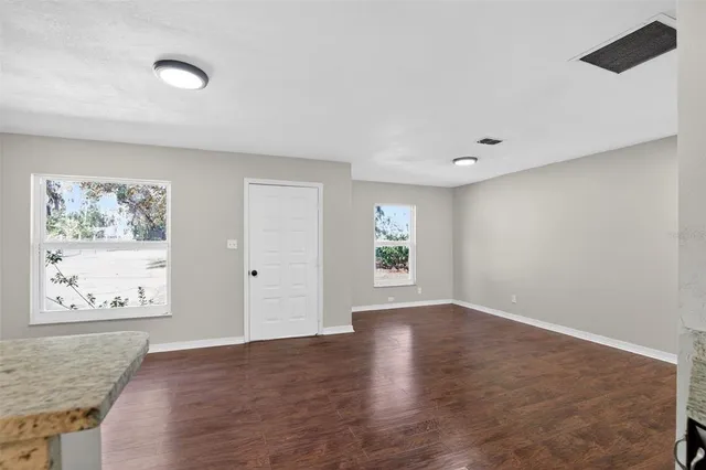 a view of an empty room with a window and wooden floor