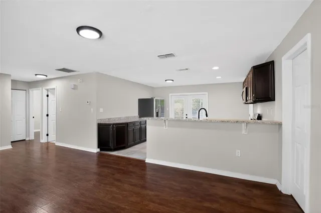 a view of kitchen with stainless steel appliances granite countertop a stove top oven and a wooden floor