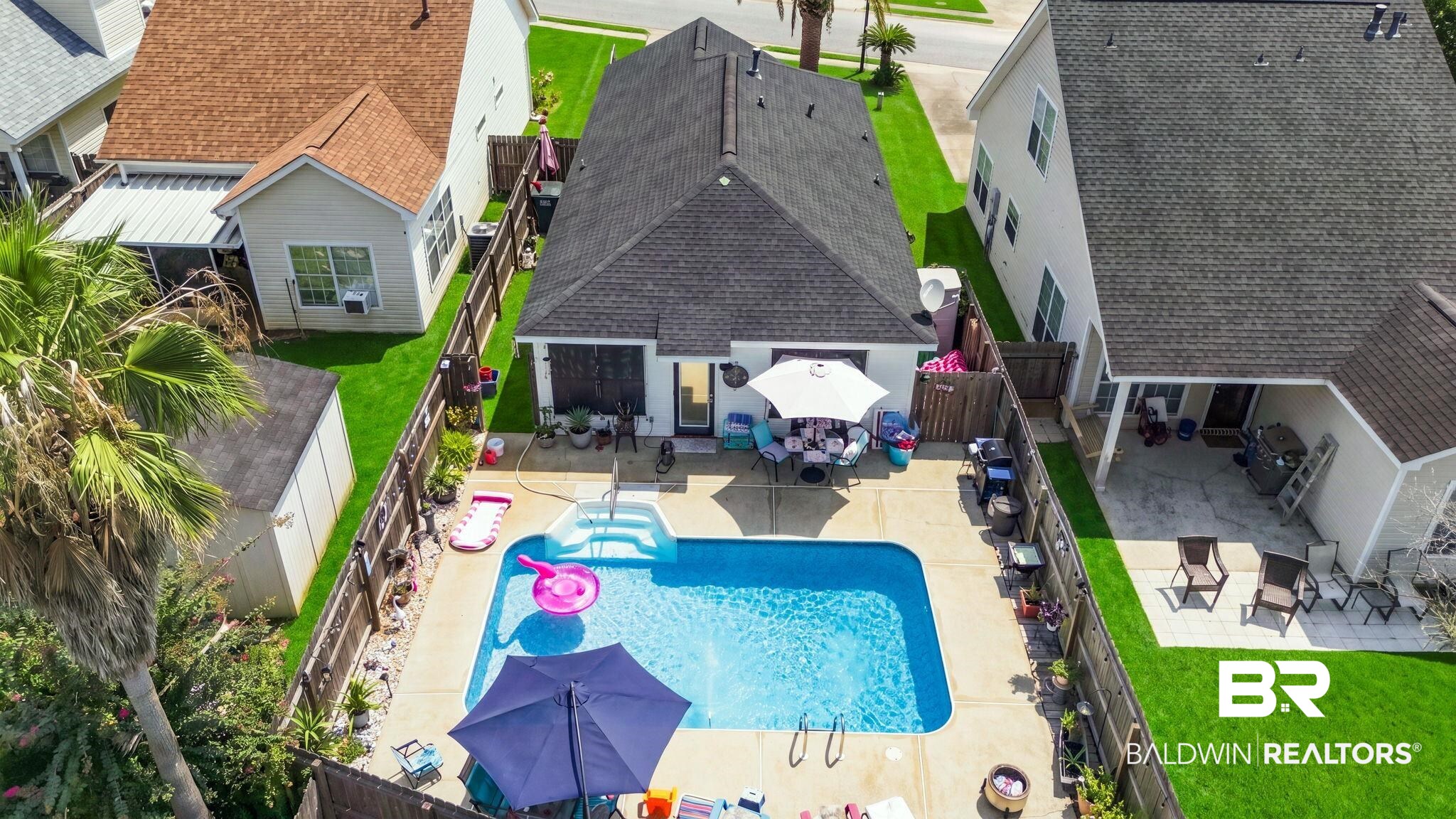 7577 Audubon Drive Foley, AL 36535 - Photo 1 of 33 Private backyard featuring a rectangular swimming pool with integrated steps, concrete patio surround, and lush green lawn