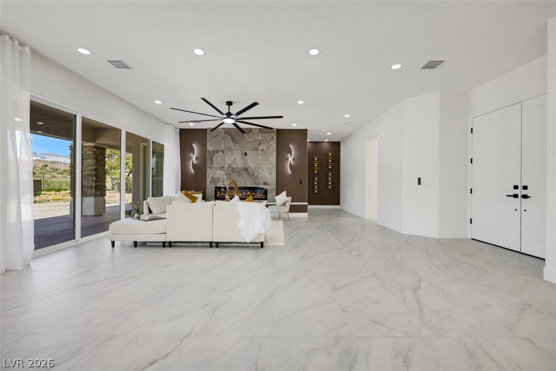 5015 Rivedro Street Las Vegas, NV 89135 - Photo 90 of 91 An inviting open floorplan living area featuring a striking fireplace and expansive sliding glass doors.