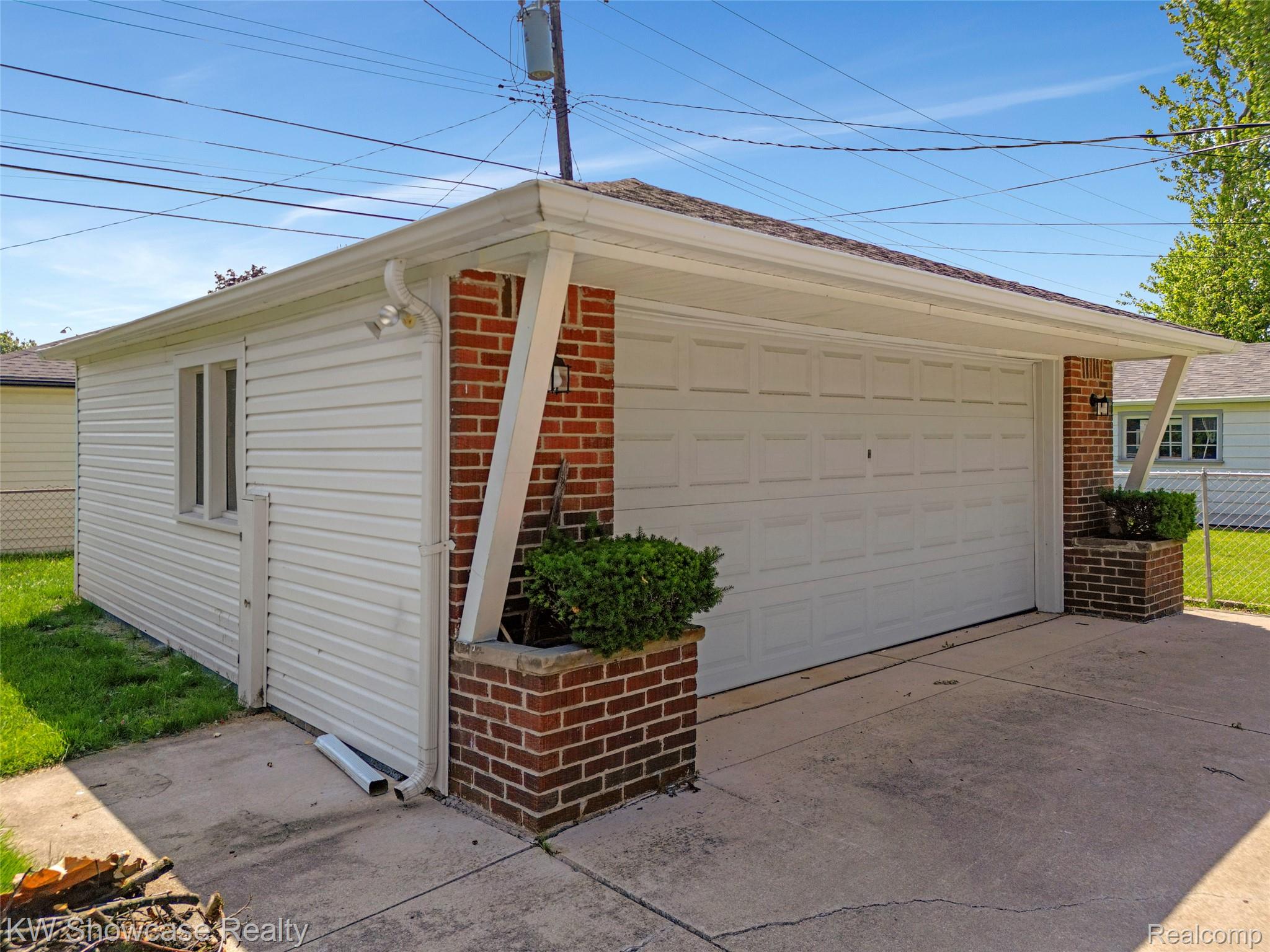 8936 Merriman Road Livonia, MI 48150 - Photo 11 of 49 Detached garage featuring a white paneled door, brick accents, white horizontal siding, a window, and a concrete driveway