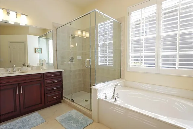 a bathroom with a granite countertop tub sink shower and mirror