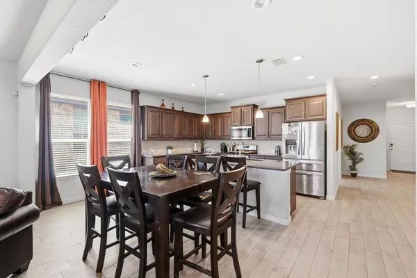 a kitchen with a dining table chairs and refrigerator
