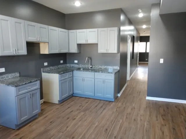 a kitchen with stainless steel appliances granite countertop a sink a stove and a wooden floors