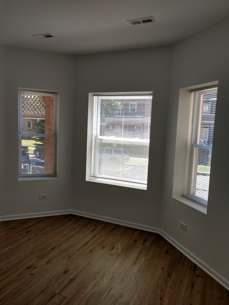 6219 South Rhodes Avenue Chicago, IL 60637 - Photo 5 of 24 a view of an empty room with wooden floor and a window
