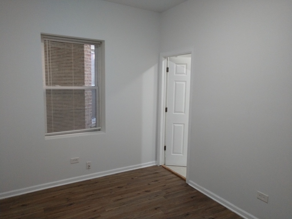 6219 South Rhodes Avenue Chicago, IL 60637 - Photo 10 of 24 a view of an empty room with wooden floor and a window