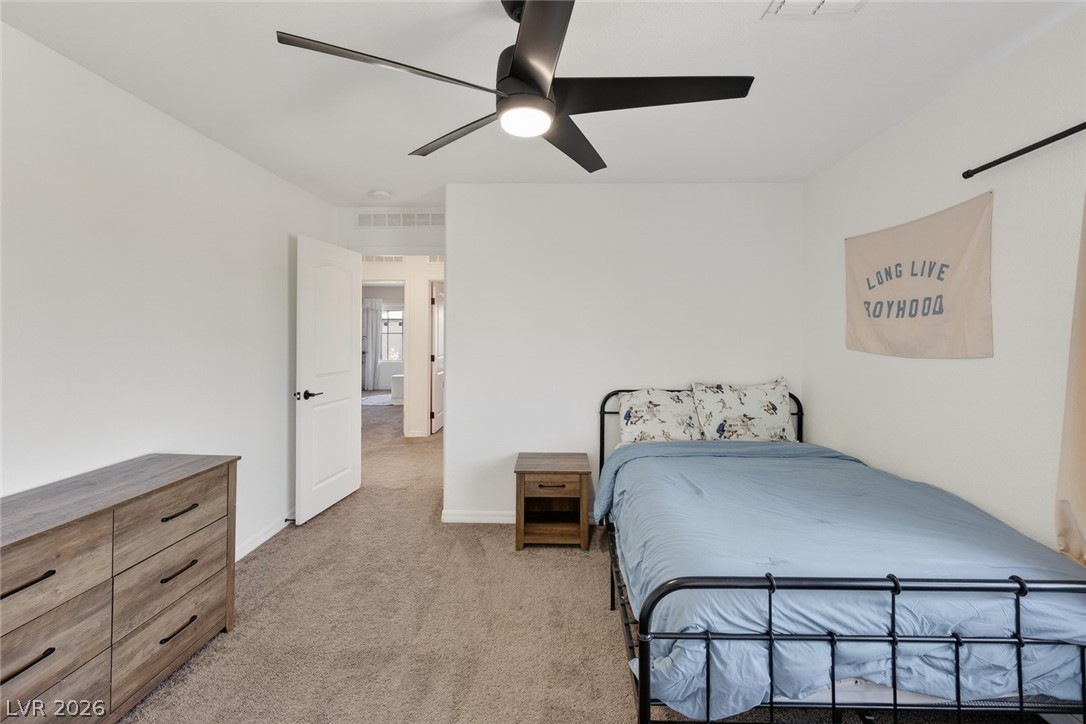 10446 Emerald Rye Street Las Vegas, NV 89183 - Photo 28 of 37 A well-lit bedroom features plush carpeting and a modern ceiling fan for ultimate comfort.