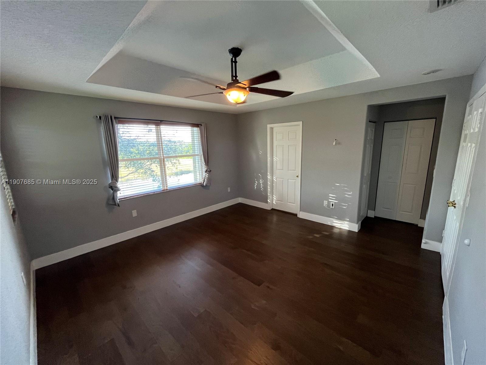 4790 Southwest 165th Avenue Miramar, FL 33027 - Photo 16 of 31 an empty room with wooden floor chandelier fan and windows