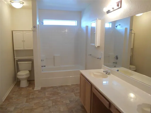 a spacious bathroom with a bathtub shower sink mirror and toilet