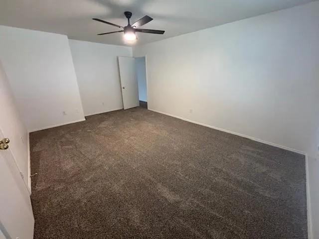en empty room with ceiling fan and window