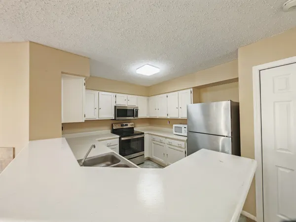 a kitchen with stainless steel appliances a refrigerator sink and white cabinets