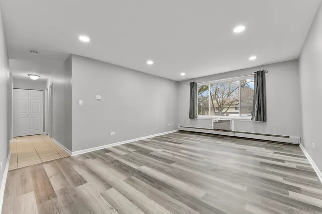 a view of an empty room with a window and wooden floor