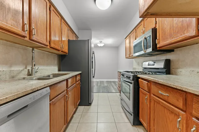 a kitchen with stainless steel appliances granite countertop a sink and dishwasher a stove top oven with wooden floor