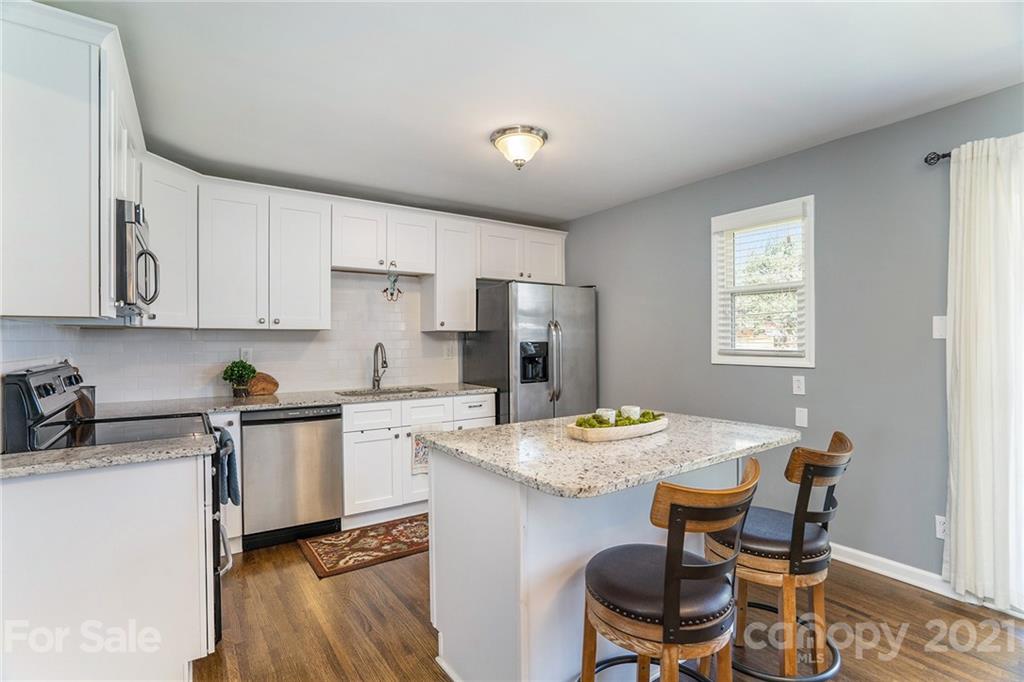 4235 Sudbury Road Charlotte, NC 28205 - Photo 5 of 29 a kitchen with a dining table chairs and refrigerator