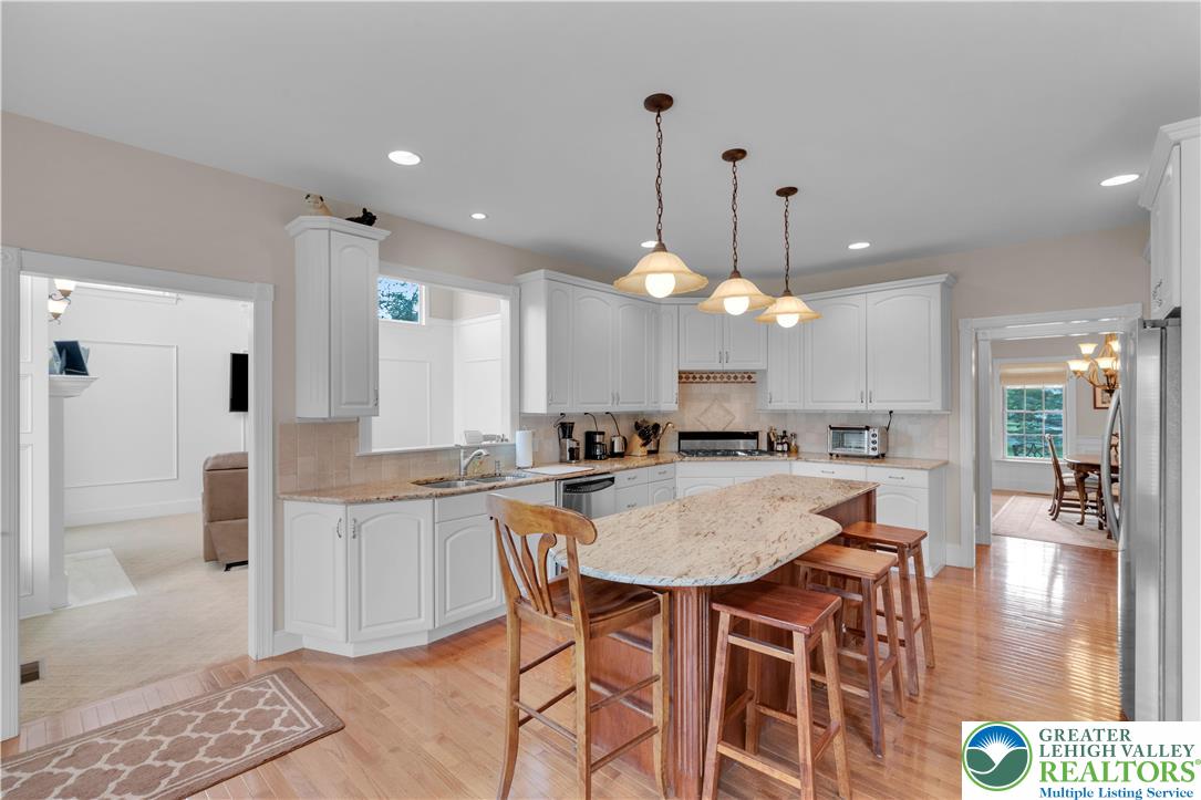 774 Lahr Road Nazareth, PA 18064 - Photo 17 of 58 a kitchen with stainless steel appliances kitchen island granite countertop a stove a refrigerator a sink a dining table and chairs with wooden floor