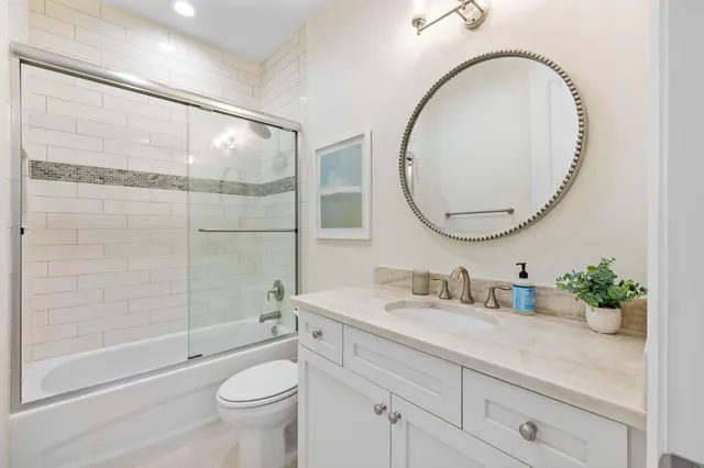 a bathroom with a granite countertop toilet a sink and a mirror