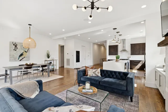 a living room with furniture kitchen view and a chandelier