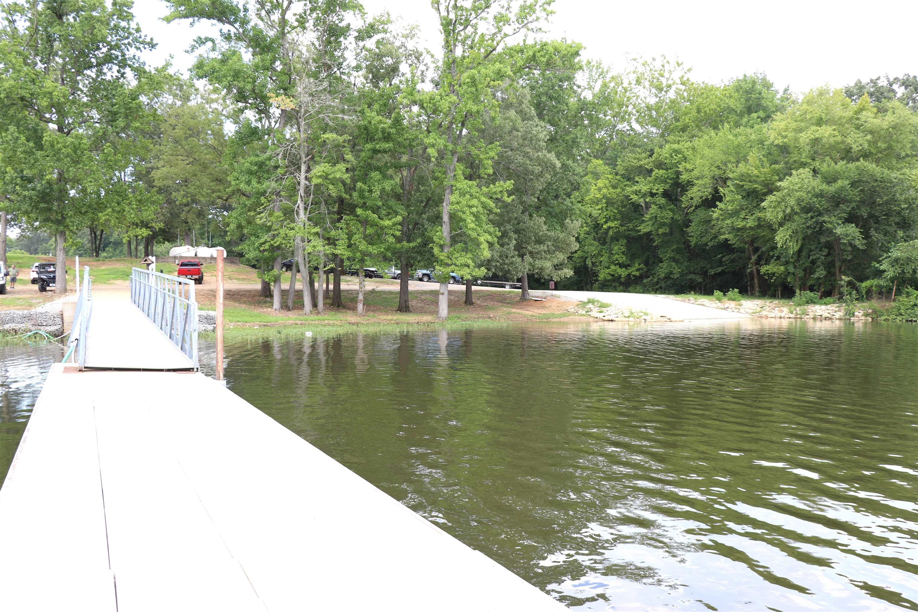 160 Patrick Drive Springville, TN 38256 - Photo 30 of 34 Dock with metal handrails extending over water, bordered by a treeline and a visible boat launch