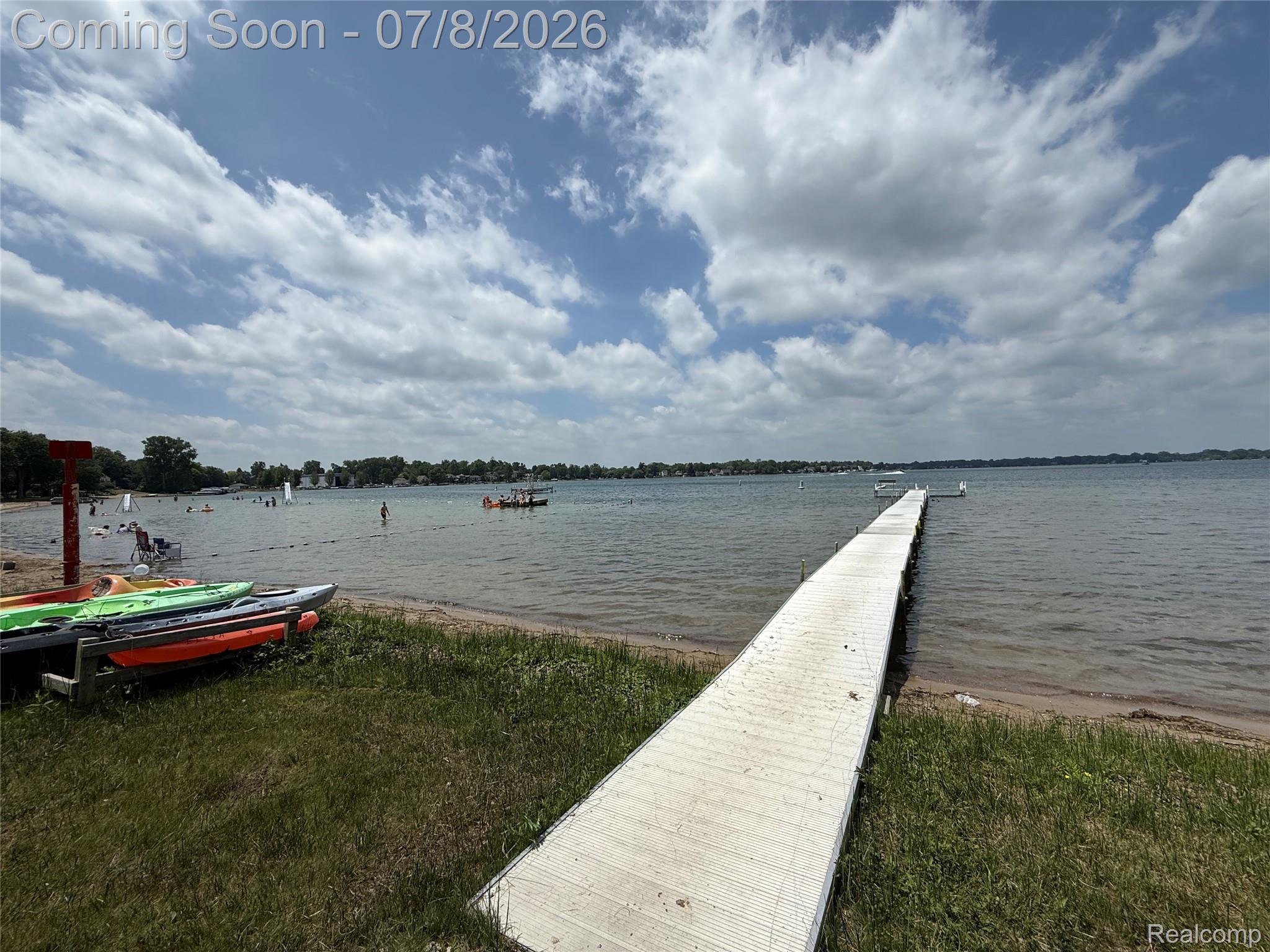 756 Cedarlawn Road Waterford, MI 48328 - Photo 22 of 34 Expansive lakefront setting featuring a long pier extending into the water, a sandy beach area, and a grassy shoreline