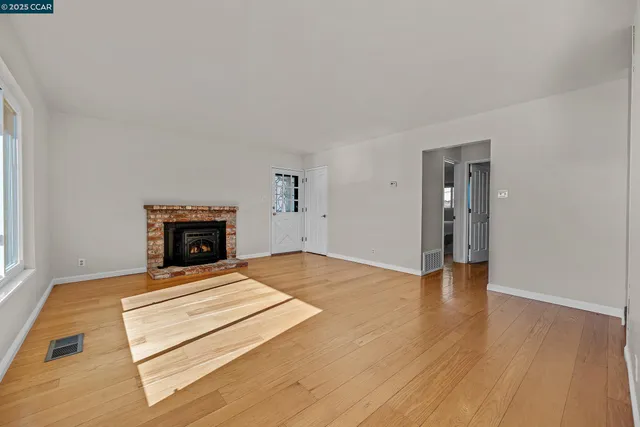 a view of empty room with wooden floor and fireplace