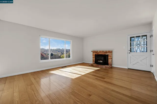 a view of an empty room with a window and fireplace