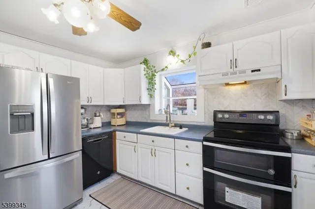 a kitchen with granite countertop white cabinets and stainless steel appliances