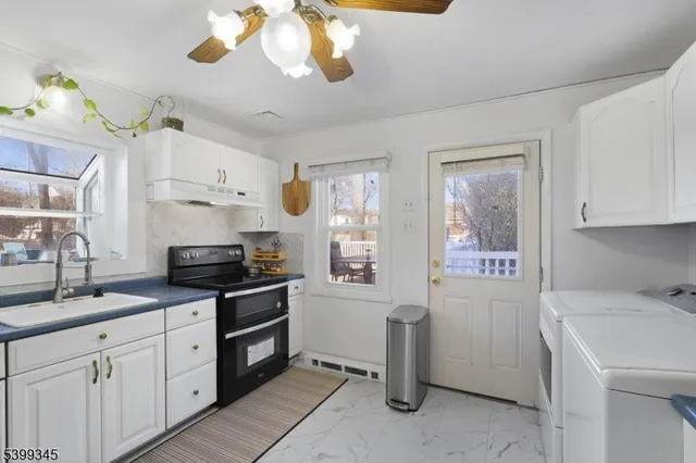 a kitchen with stainless steel appliances a stove a sink and white cabinets