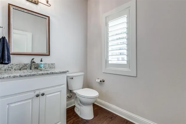 a bathroom with a granite countertop toilet a sink and a mirror