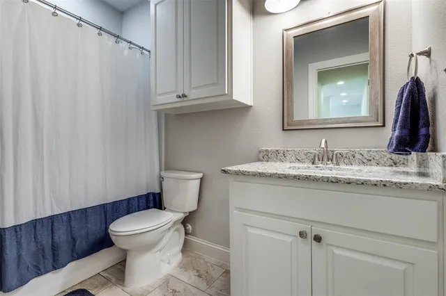 a bathroom with a granite countertop sink toilet and mirror