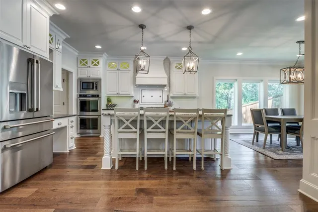 a dining room with stainless steel appliances kitchen island granite countertop a table chairs and a refrigerator