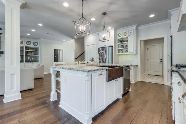 a large kitchen with a large counter top space a sink stainless steel appliances and wooden floor