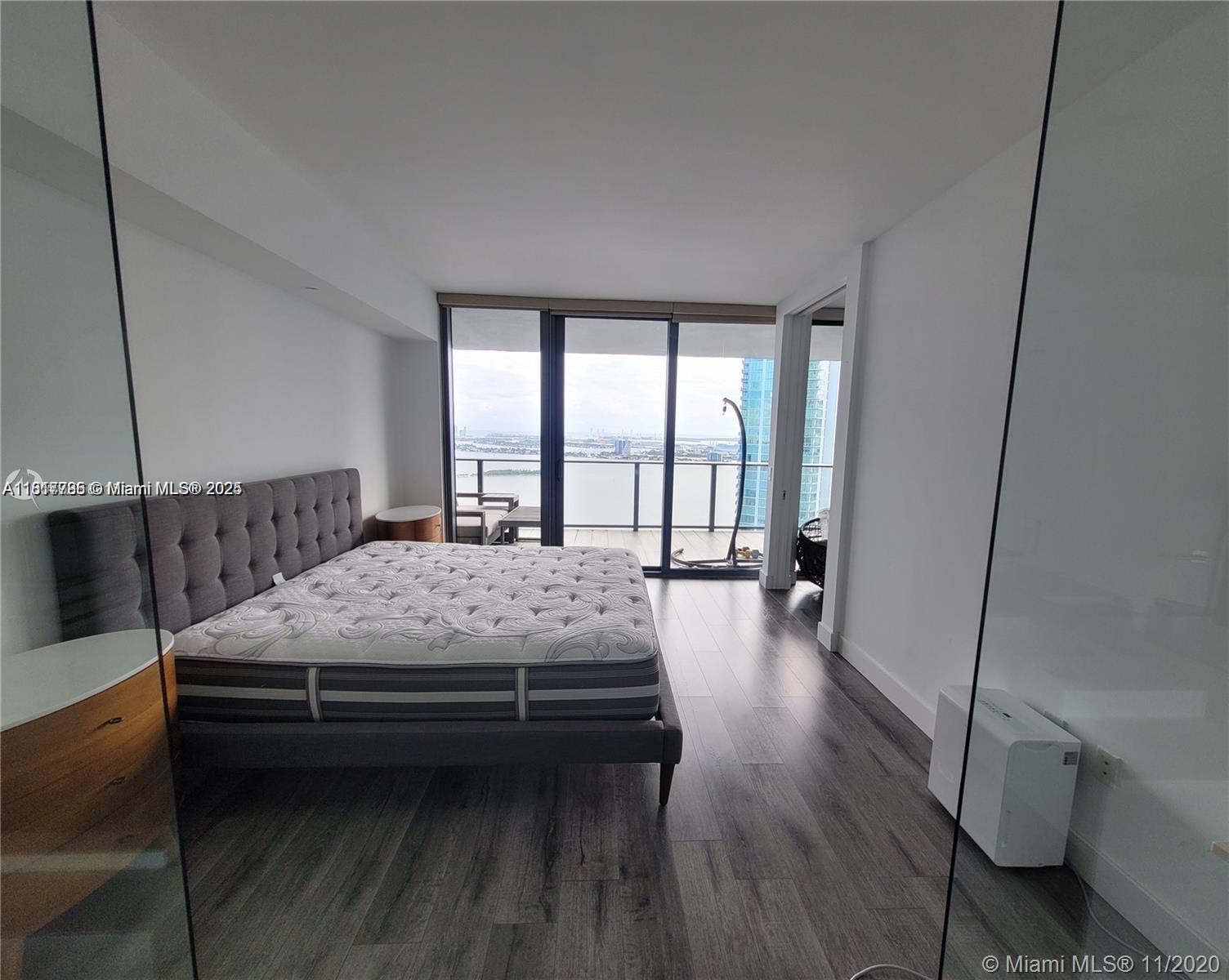 Edgewater Miami, FL 33137 - Photo 7 of 11 a bedroom with a bed wooden floor and a large window