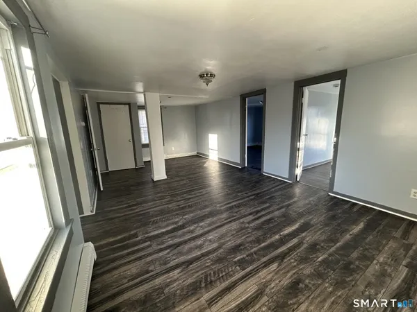 a view of an empty room with wooden floor and a window
