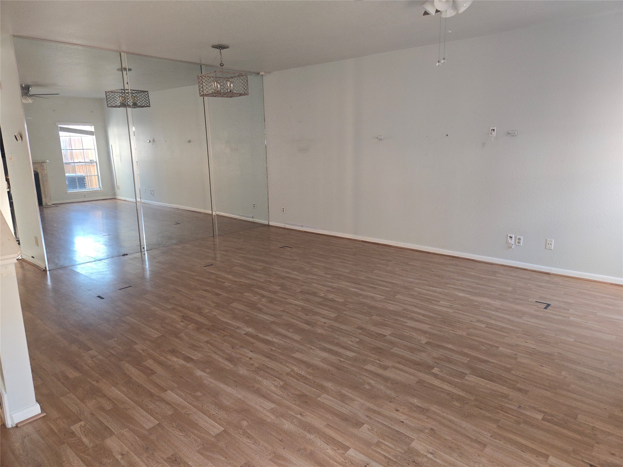 3780 Tanglewilde Street, Unit 501 Houston, TX 77063 - Photo 15 of 26 This spacious room features laminate wood flooring and mirrored walls, creating an open and airy feel. The large window provides natural light, while a ceiling fan and modern lighting add style and comfort. Perfect for a versatile living area or home office.