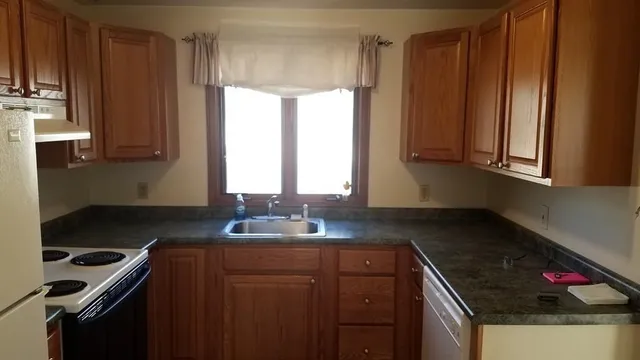 a kitchen with granite countertop a sink stove and cabinets