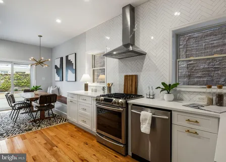 a kitchen with a sink stainless steel appliances and dining table with wooden floor