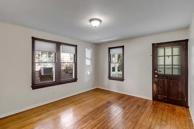 a view of an empty room with a window and wooden floor