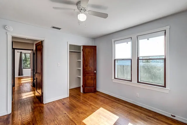 a view of an empty room with a window and wooden floor