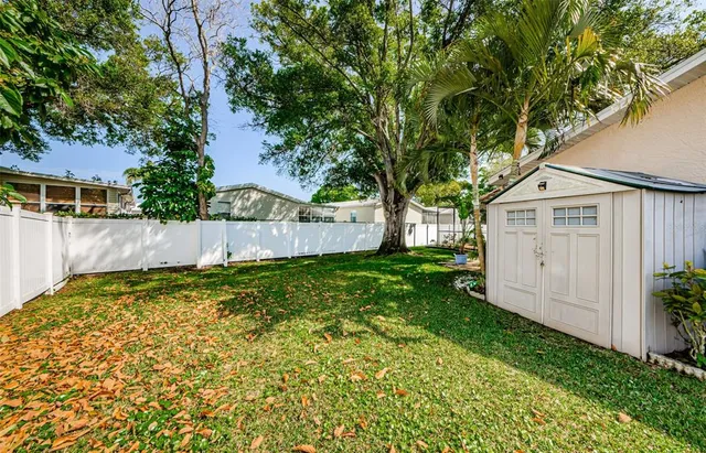 a view of a backyard with plants and large trees