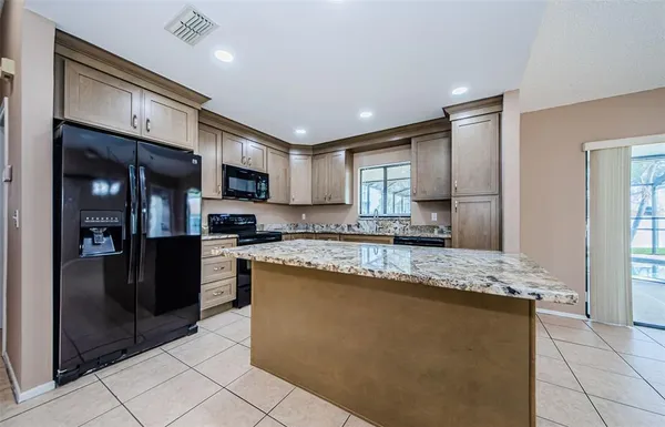 a large kitchen with stainless steel appliances granite countertop a refrigerator and a stove top oven