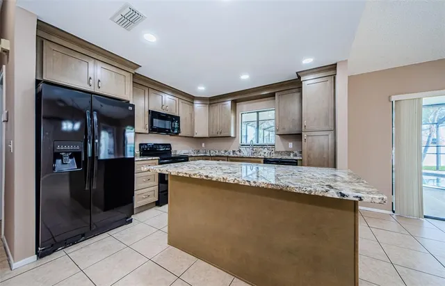 a large kitchen with stainless steel appliances granite countertop a refrigerator and a stove top oven