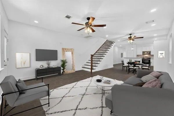an empty room with wooden floor fan and windows