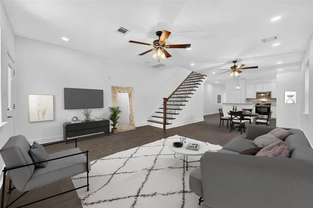 an empty room with wooden floor fan and windows