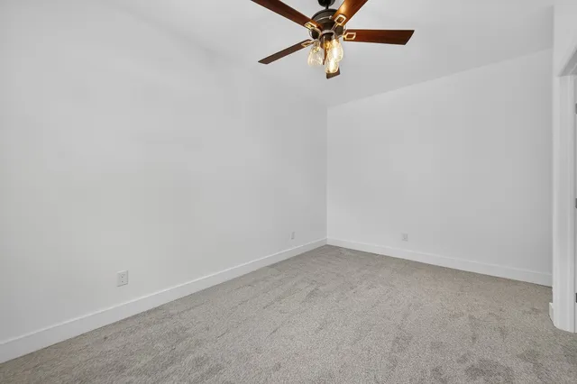 a view of a livingroom with a ceiling fan & windows