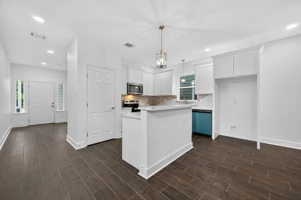 a kitchen with stainless steel appliances granite countertop a sink a stove a refrigerator and white cabinets with wooden floor