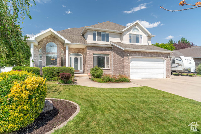 2478 Bluff Ridge Drive Syracuse, UT 84075 - Photo 1 of 1 View of front facade with driveway, a garage, a front yard, brick siding, and a shingled roof