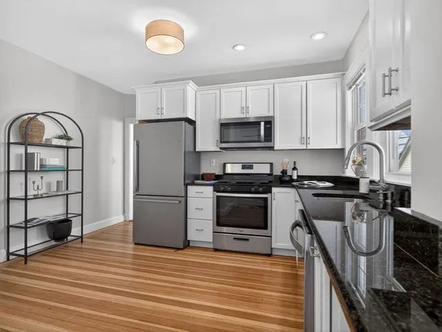 a kitchen with granite countertop a stove a refrigerator and a sink with wooden floor